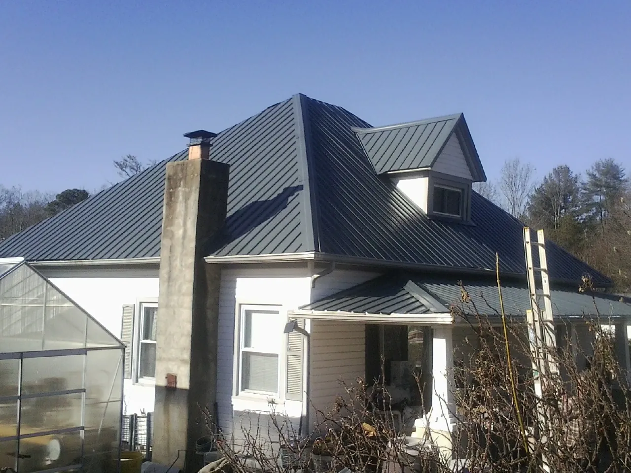 Dark blue standing seam metal roof on a white farmhouse with dormer — Slate & Tile Roof Repair by Roofing Brothers in Ione