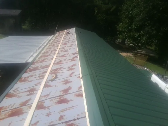 Old rusted panels beside newly installed green metal roofing — Wind Damage Roof Repair by Roofing Brothers in Ione
