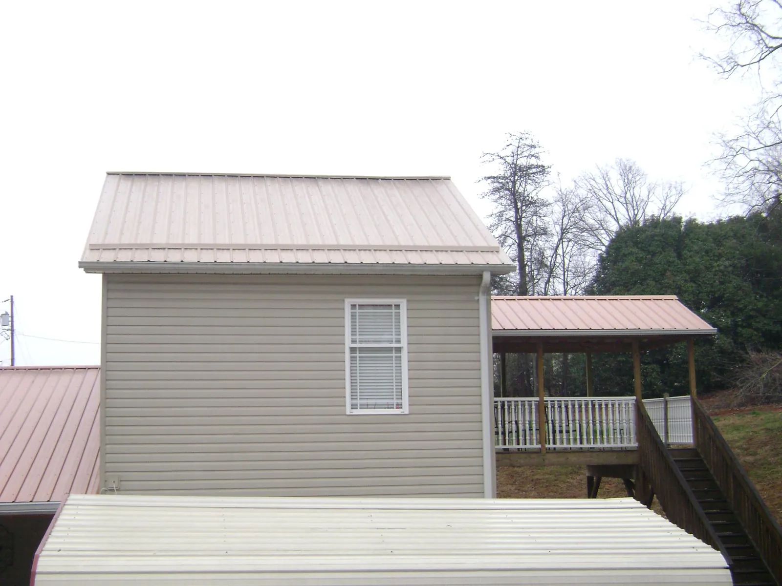 Tan metal roofs on a two story addition and attached porch, from a Roof Replacement job in Ione